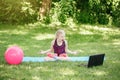 Angry mad girl child doing sport workout outdoor online. Video yoga class on Internet. Funny stressed kid training in park with Royalty Free Stock Photo