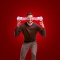 An angry man in casual outfit leaning forward with steam coming out of his ears on red background.