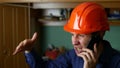 Angry man construction worker in a hardhat shouting, talking on phone smartphone Royalty Free Stock Photo