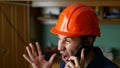 Angry man construction worker in a hardhat shouting, talking on the phone smartphone Royalty Free Stock Photo