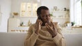 Angry man discusses with colleague by phone sitting on sofa Royalty Free Stock Photo