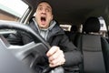 Angry man driving a car. Male driver gesturing and shouting behind the wheel of the car. Royalty Free Stock Photo