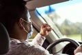 An angry man with his fist up high drives his car with a mask on Royalty Free Stock Photo