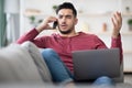 Angry man with notebook on his lap having phone conversation