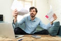 Angry man paying bills as home with laptop and calculator