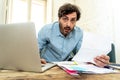 Angry man paying bills as home with laptop and calculator