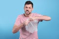Angry man popping bubble wrap on light blue background. Stress relief Royalty Free Stock Photo