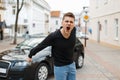 Angry man screams near a car in the city.