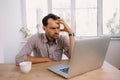 Angry man in shirt with a cup of coffee works on laptop