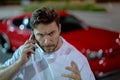 Angry man talking on phone near car on night urban street. Dangerous aggressive man talking on phone with serious face Royalty Free Stock Photo