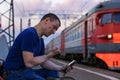 Angry man threatens with his fist in the smartphone at the station near the train