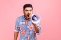 Angry man wearing casual blue shirt holding megaphone near mouth loudly speaking, screaming, making announcement, paying attention Royalty Free Stock Photo