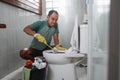 angry man wearing gloves brushing smelly toilet Royalty Free Stock Photo