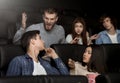 Angry man yelling at young man with mobile phone in cinema Royalty Free Stock Photo