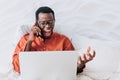 Angry executive African American businessman shouts into his phone at his subordinates and looks at his laptop while Royalty Free Stock Photo