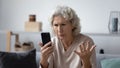 Angry senior woman frustrated by smartphone problems Royalty Free Stock Photo