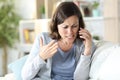 Angry middle age woman arguing calling on phone at home