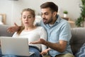 Angry millennial couple having computer problems at home