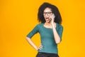 Angry mixed race caucasian - african american woman shouting in mobile phone, isolated over yellow background Royalty Free Stock Photo