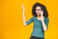 Angry mixed race caucasian - african american woman shouting in mobile phone, isolated over yellow background Royalty Free Stock Photo