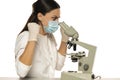 Angry nervous female scientist with protective face mask looking through a microscope