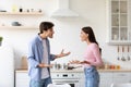 Angry offended young wife and husband shout, swear in kitchen interior. Couple arguing and conflicting
