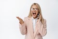 Angry office lady shouting, having an argument on phone, screaming and fighting with caller, standing in suit against Royalty Free Stock Photo