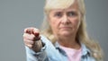 Angry old woman pointing by finger in camera, condemnation gesture, disapproval