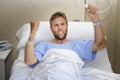 Angry patient man at hospital room lying in bed pressing nurse call button feeling nervous and upset