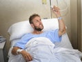 Angry patient man at hospital room lying in bed pressing nurse call button feeling nervous and upset