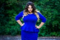 Angry plus size fashion model in blue dress outdoors, beauty woman with professional makeup and hairstyle Royalty Free Stock Photo