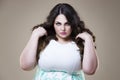 Angry plus size fashion model, fat woman on beige background, overweight female body Royalty Free Stock Photo