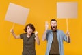 Angry protesting people guy girl hold protest signs broadsheet blank placard on stick isolated on yellow background