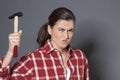 Angry 30s woman holding hammer for aggression or self-defense Royalty Free Stock Photo