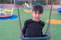 Angry sad boy sitting on swing