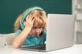 Angry sad child using laptop computer, kid boy studying through online e-learning. Little funny system administrator. Royalty Free Stock Photo