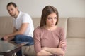 Angry sad woman standing with arms crossed, man in background