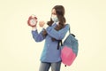 Angry school child in face mask punch alarm clock during COVID-19 disease pandemic, ultimatum