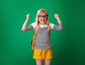 Angry school girl with backpack isolated on green background