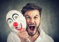 Angry screaming man taking off a clown mask Royalty Free Stock Photo