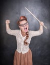 Angry screaming teacher with pointer on the chalkboard background