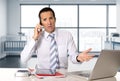 Angry senior businessman in stress working and talking on mobile phone at computer desk Royalty Free Stock Photo