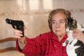 Angry senior woman protecting her cat with a gun Royalty Free Stock Photo