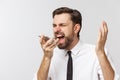 Angry and serious businessman talking on the phone over gray background Royalty Free Stock Photo