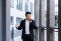 Angry and serious Successful Asian businessman explains information to employees using phone, speaks near office outside Royalty Free Stock Photo