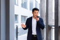 Angry and serious Successful Asian businessman explains information to employees using phone, speaks near office outside Royalty Free Stock Photo