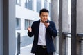 Angry and serious Successful Asian businessman explains information to employees using phone, speaks near office outside Royalty Free Stock Photo