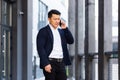 Angry and serious Successful Asian businessman explains information to employees using phone, speaks near office outside Royalty Free Stock Photo