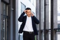 Angry and serious Successful Asian businessman explains information to employees using phone, speaks near office outside Royalty Free Stock Photo