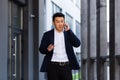 Angry and serious Successful Asian businessman explains information to employees using phone, speaks near office outside Royalty Free Stock Photo